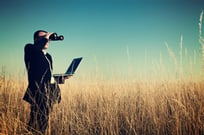 A man in a field looking through binoculars